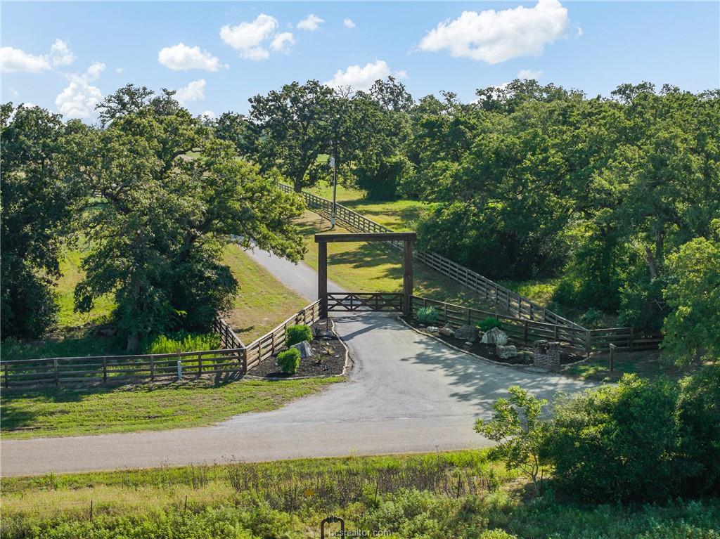 Gated ranch entrance and tree-lined drive at 4845 County Road 119 near Caldwell, Texas