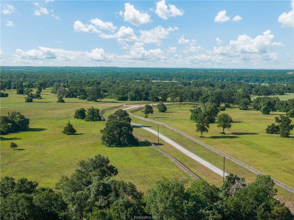 Aerial view of the fenced ranch drive crossing open pasture at 4845 County Road 119 near Caldwell, Texas